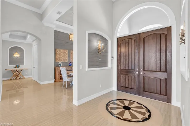 Foyer entrance with ornamental molding, light hardwood / wood-style flooring, and a chandelier