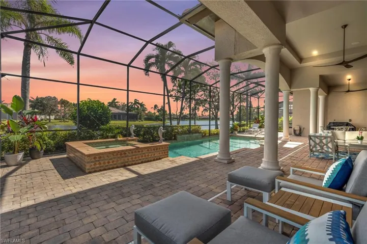 Patio terrace at dusk featuring a pool with hot tub, ceiling fan, and glass enclosure