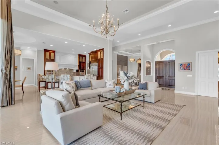 Living room with crown molding, a notable chandelier, and a tray ceiling