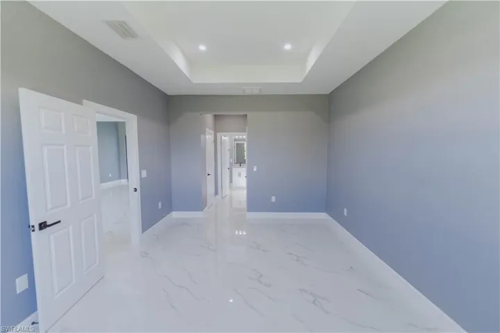 Empty room featuring light tile patterned flooring and a tray ceiling