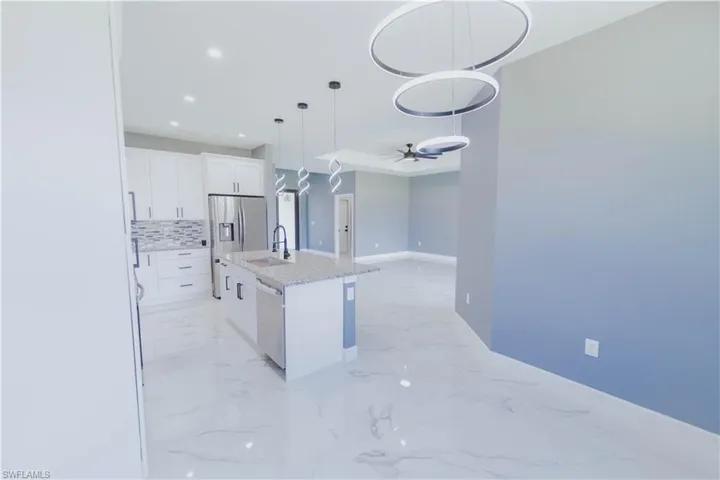 Kitchen featuring sink, pendant lighting, light tile patterned floors, and an island with sink