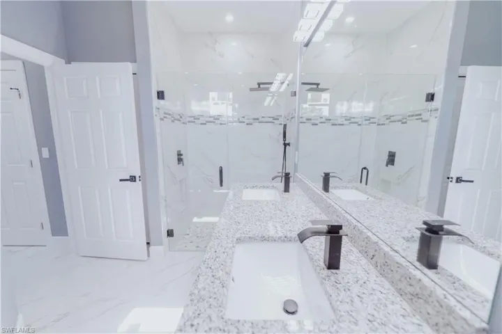 Bathroom with tile patterned floors, double sink vanity, and walk in shower