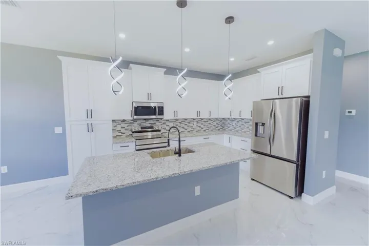 Kitchen featuring white cabinets, light tile patterned floors, backsplash, and stainless steel appliances