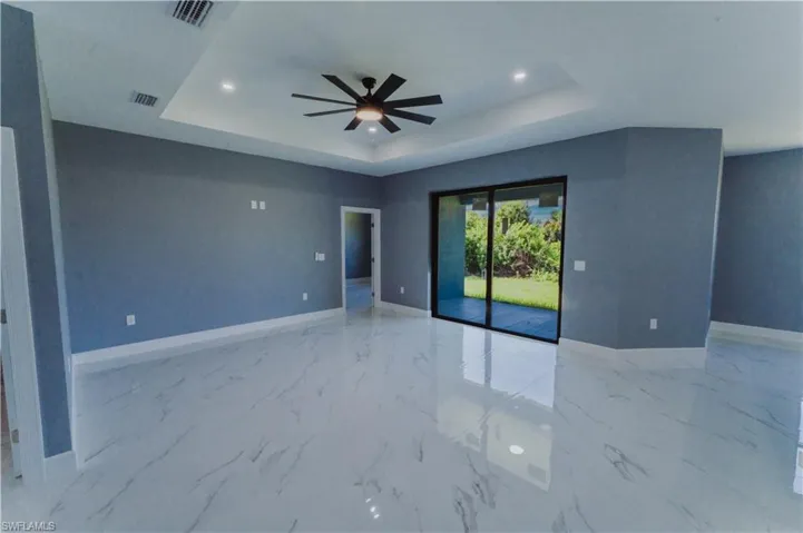 Unfurnished room featuring ceiling fan, a tray ceiling, and tile patterned floors