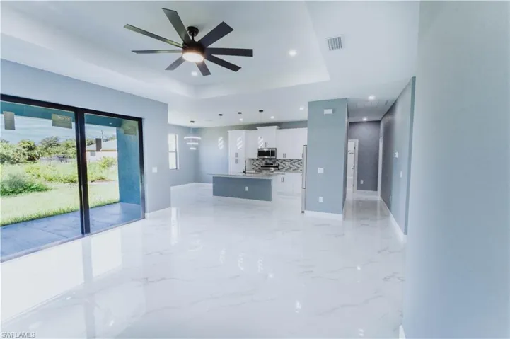 Kitchen with hanging light fixtures, a center island, white cabinetry, ceiling fan, and a raised ceiling