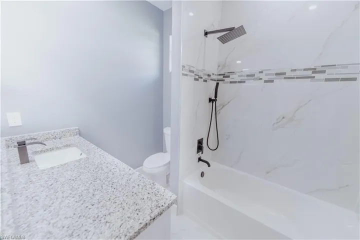 Full bathroom featuring vanity, tiled shower / bath, tile patterned flooring, and toilet