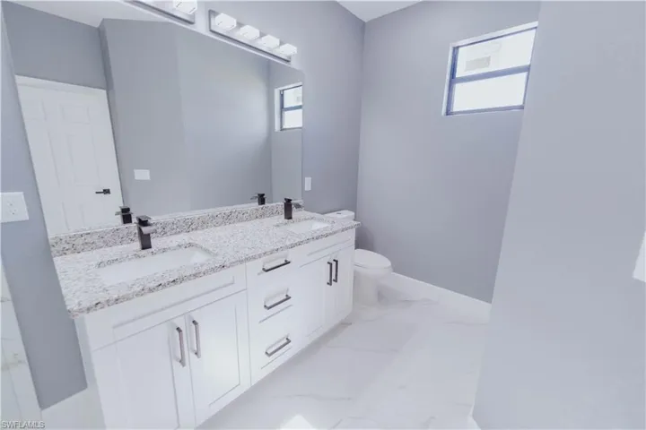 Bathroom featuring toilet, tile patterned floors, and double vanity