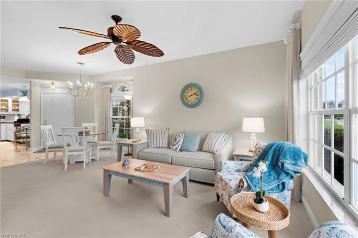 Living room with light colored carpet and ceiling fan with notable chandelier