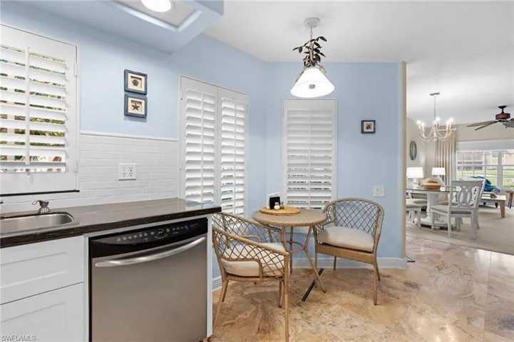 Kitchen with ceiling fan with notable chandelier, pendant lighting, dishwasher, sink, and white cabinetry