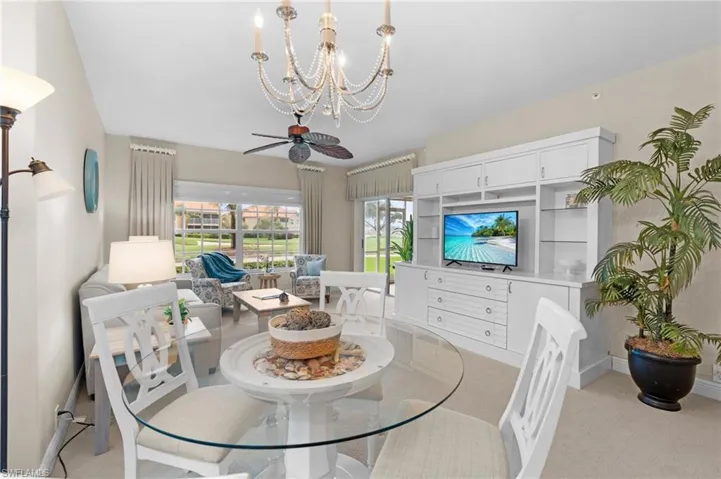 Carpeted dining area featuring ceiling fan with notable chandelier