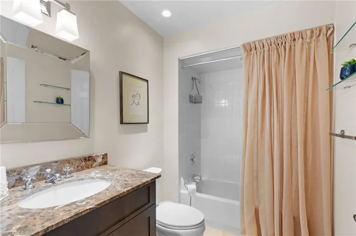 Full bathroom with toilet, vanity, and shower / bath combination with curtain