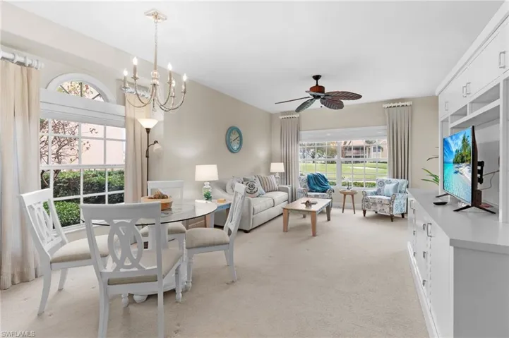 Carpeted dining space featuring ceiling fan with notable chandelier
