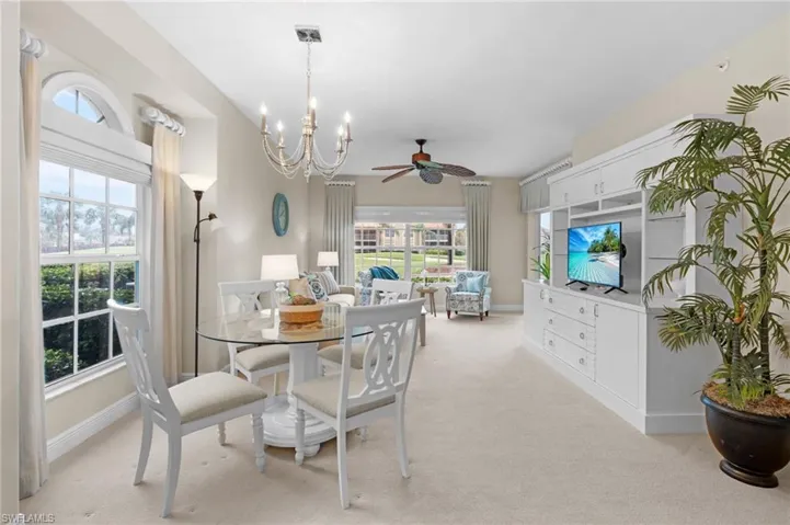 Dining space featuring ceiling fan with notable chandelier and light colored carpet