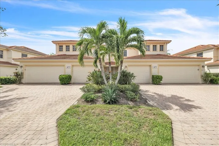 Mediterranean-style exterior featuring a tile roof, dual garage doors, and a paver driveway