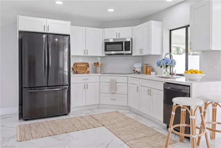 White shaker cabinetry, stainless steel appliances, and light countertops define this kitchen space