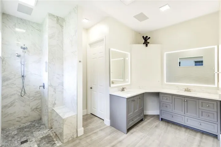 Spacious bathroom featuring a walk-in shower with marble-look tile, a built-in shower bench, and pebble-finish shower flooring