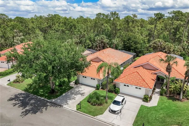 Aerial perspective showcasing two properties with terracotta tile roofs, each featuring a white garage door and concrete driveway