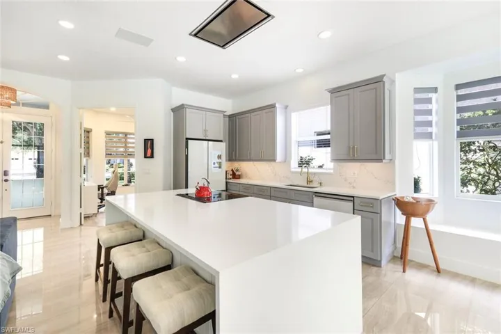 Gourmet kitchen featuring a large white island with cooktop, light gray cabinetry, white countertops, and a full suite of stainless steel appliances