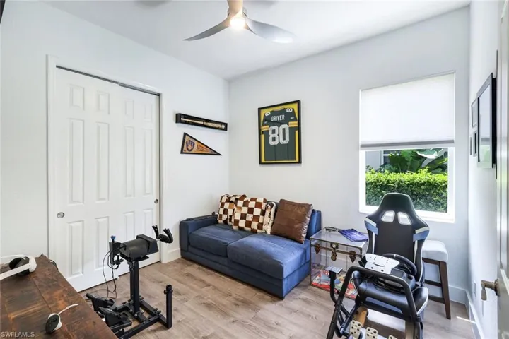 Bright interior space featuring wood-finish flooring, a white paneled sliding closet door, and a modern ceiling fan