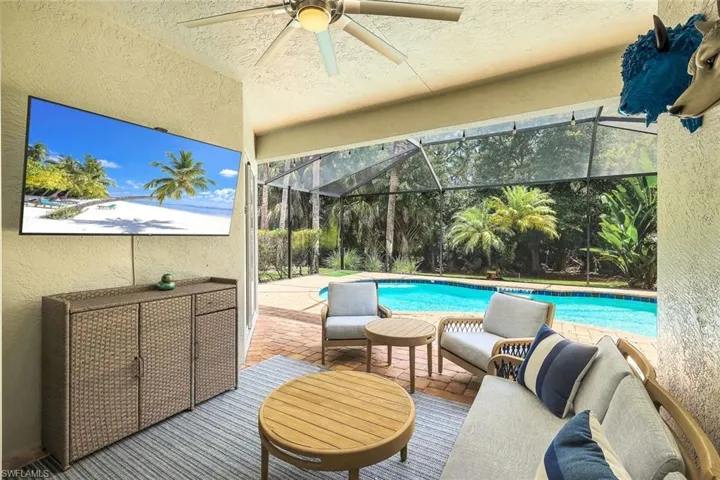 Covered patio featuring a ceiling fan, brick paver flooring, and a flat-screen television