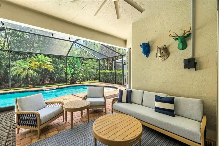 Screened pool patio featuring a rectangular swimming pool with brick paver decking, a textured wall finish, and a ceiling fan