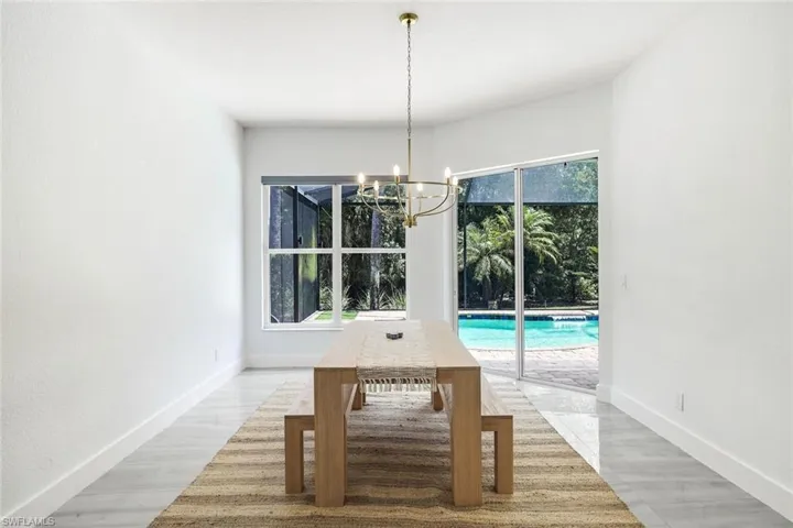 Dining area featuring a contemporary chandelier, large picture window, sliding glass doors, and light-toned flooring