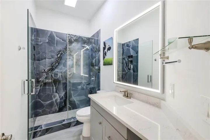 Walk-in shower with frameless glass enclosure and dramatic dark-toned tile