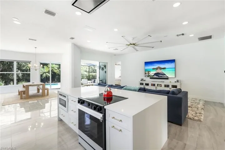 Central kitchen island with a built-in electric cooktop, microwave, and white cabinetry
