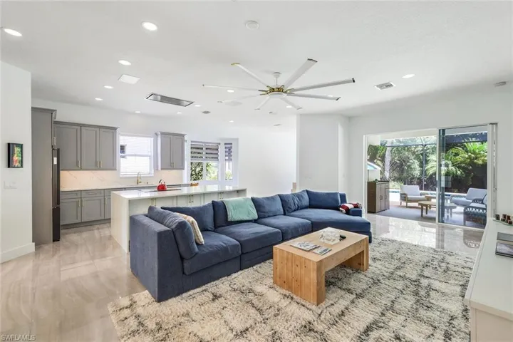 Spacious open-concept living area featuring light-toned flooring, recessed lighting, and a multi-blade ceiling fan