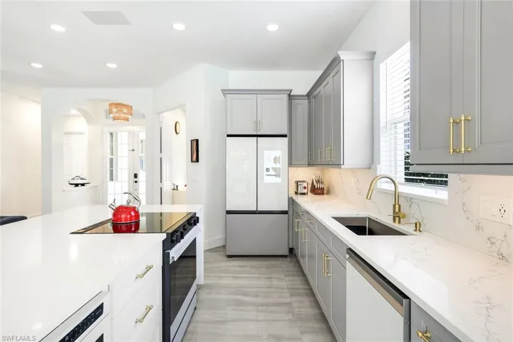 Modern kitchen featuring light gray cabinetry, white countertops, stainless steel appliances, a built-in microwave, and wood-finish flooring