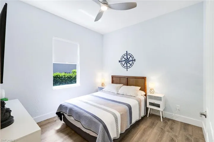 Bedroom featuring wood-finish flooring, a contemporary ceiling fan, and a single window with a roller shade