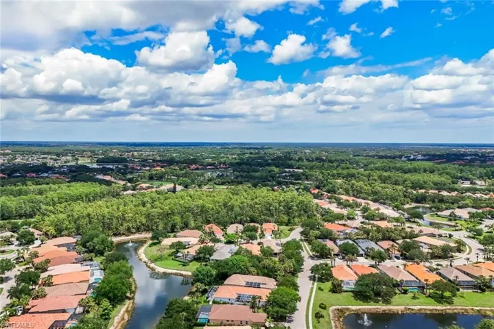 Expansive aerial perspective showcasing a residential development with multiple water features, mature landscaping, and diverse architectural styles