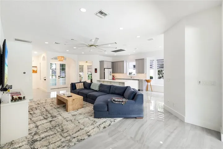 Open-concept living space featuring high ceilings with recessed lighting, a large ceiling fan, and light gray tile flooring