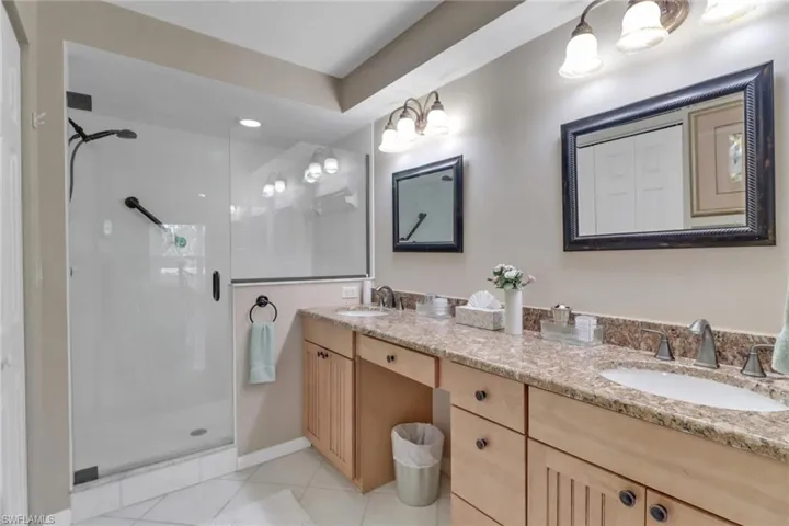 Bathroom featuring tile patterned floors, vanity, and a shower with door