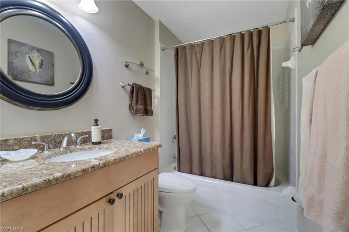 Full bathroom with tile patterned floors, shower / bath combo with shower curtain, vanity, and toilet