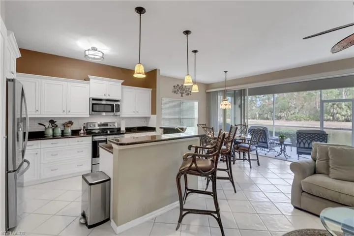 Kitchen with plenty of natural light, white cabinetry, hanging light fixtures, and appliances with stainless steel finishes
