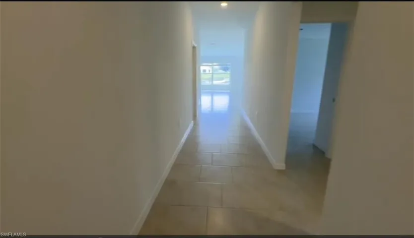Hall with baseboards and tile patterned flooring