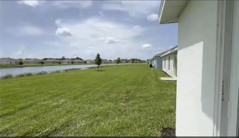 View of green lawn with a water view and a residential view