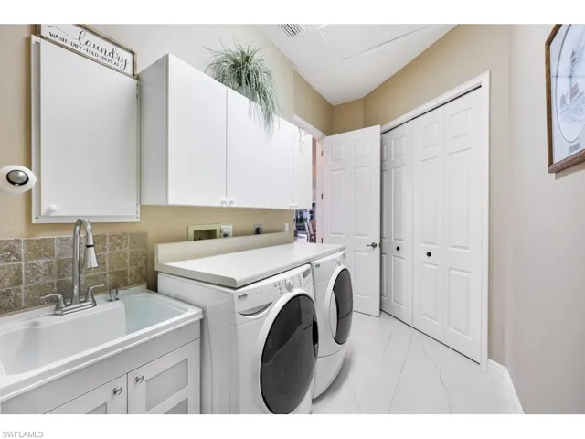 Laundry room with sink, washer and clothes dryer, and cabinets