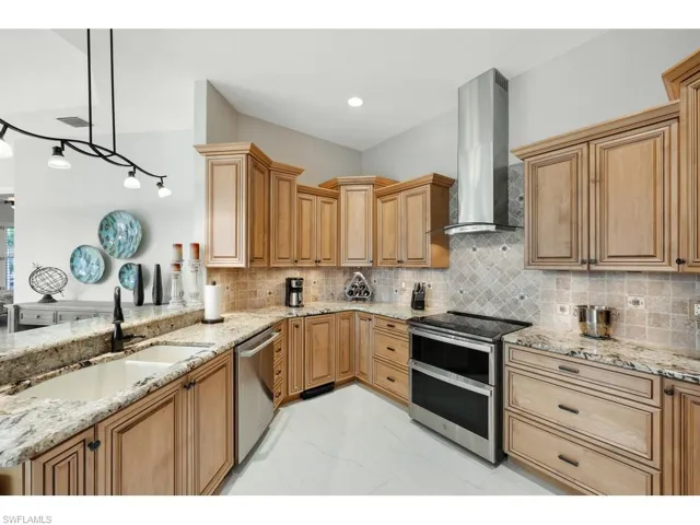 Kitchen with tasteful backsplash, custom exhaust hood, and decorative light fixtures, custom spice rack and built in cutting board, pull outs in the cabinets.