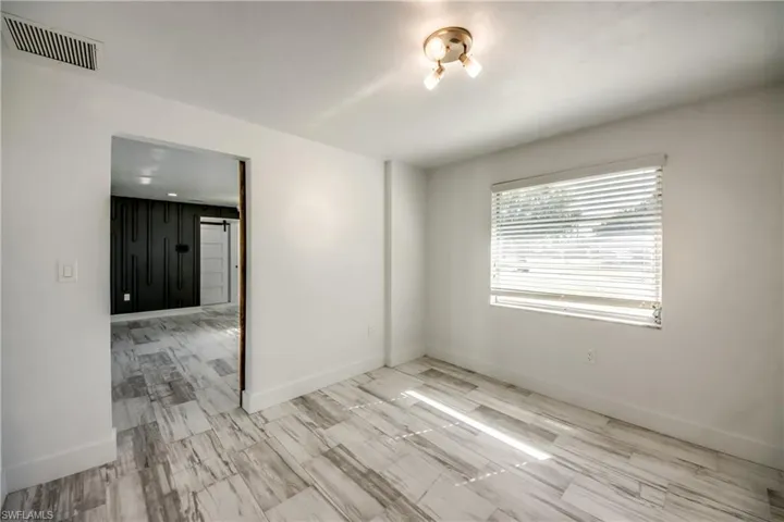 Unfurnished bedroom featuring attic access, a barn door, ceiling fan, and light wood-style flooring