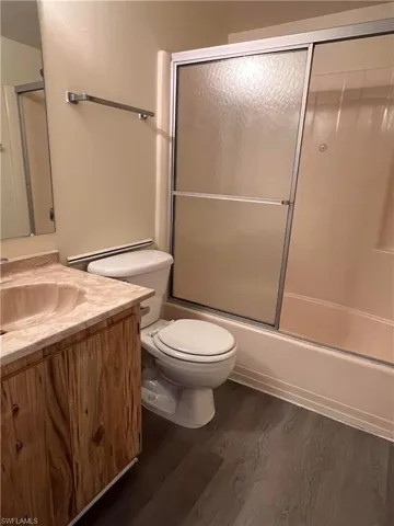 Full bath featuring vanity, enclosed tub / shower combo, and wood finished floors