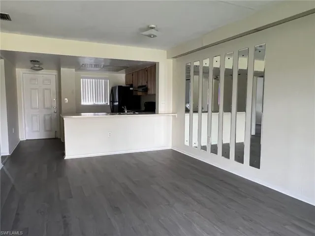 Kitchen with dark wood-type flooring, freestanding refrigerator, and under cabinet range hood