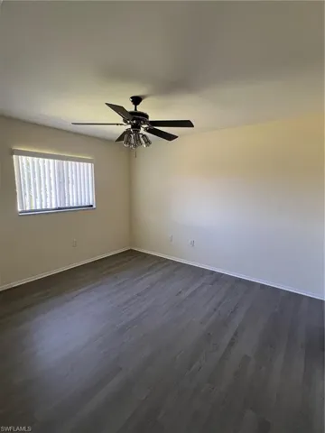 Empty room featuring dark wood-style flooring and ceiling fan