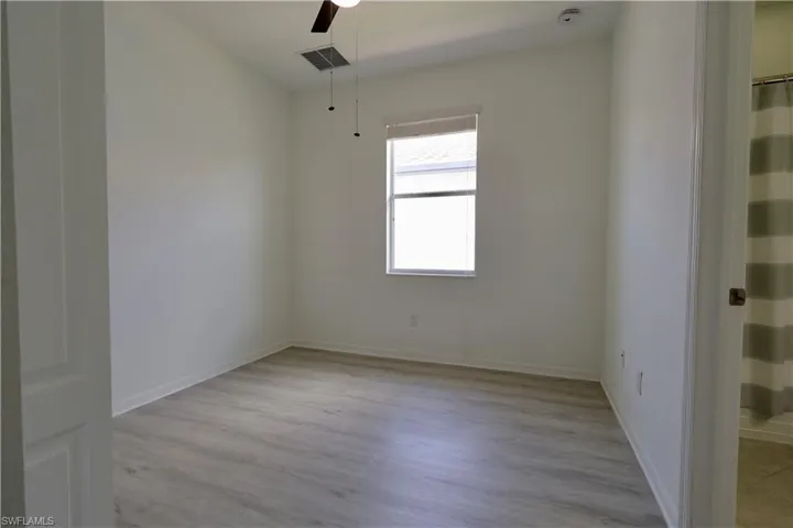 Unfurnished room with light wood-style flooring, ceiling fan, and a smoke detector