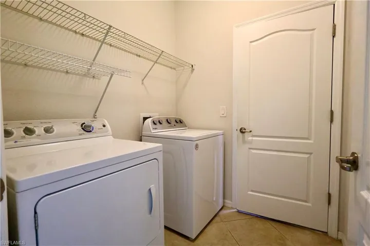 Laundry area with independent washer and dryer and light tile patterned floors