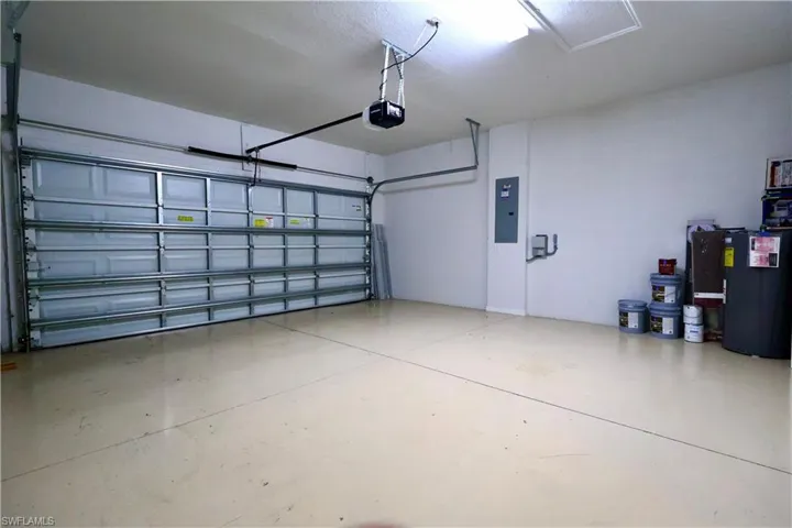 Garage featuring a garage door opener, electric panel, and water heater