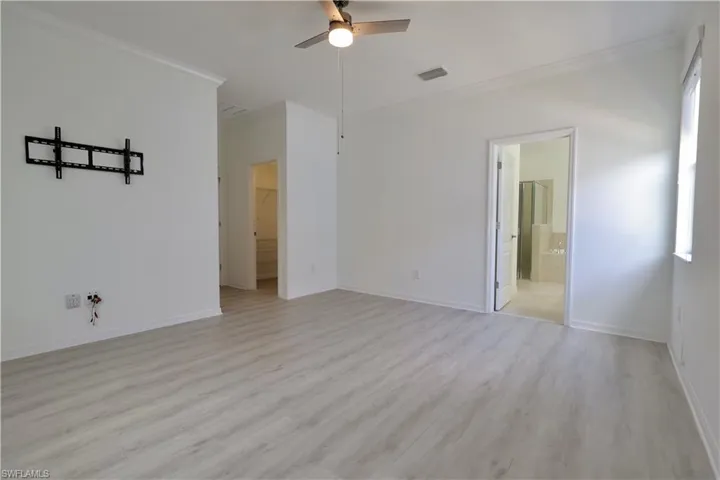 Spare room featuring ornamental molding, a ceiling fan, and light wood-type flooring