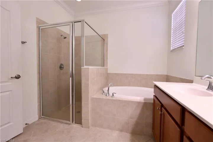 Bathroom with vanity, a shower stall, a garden tub, tile patterned flooring, and crown molding