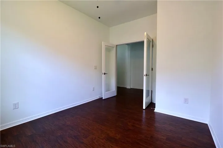 Spare room with dark wood-style flooring and baseboards